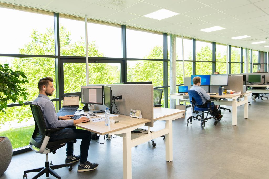 Moderne ergonomische werkplek met zit-sta bureau en verstelbare monitor Moderne ergonomische werkplek met zit-sta bureau en verstelbare monitor